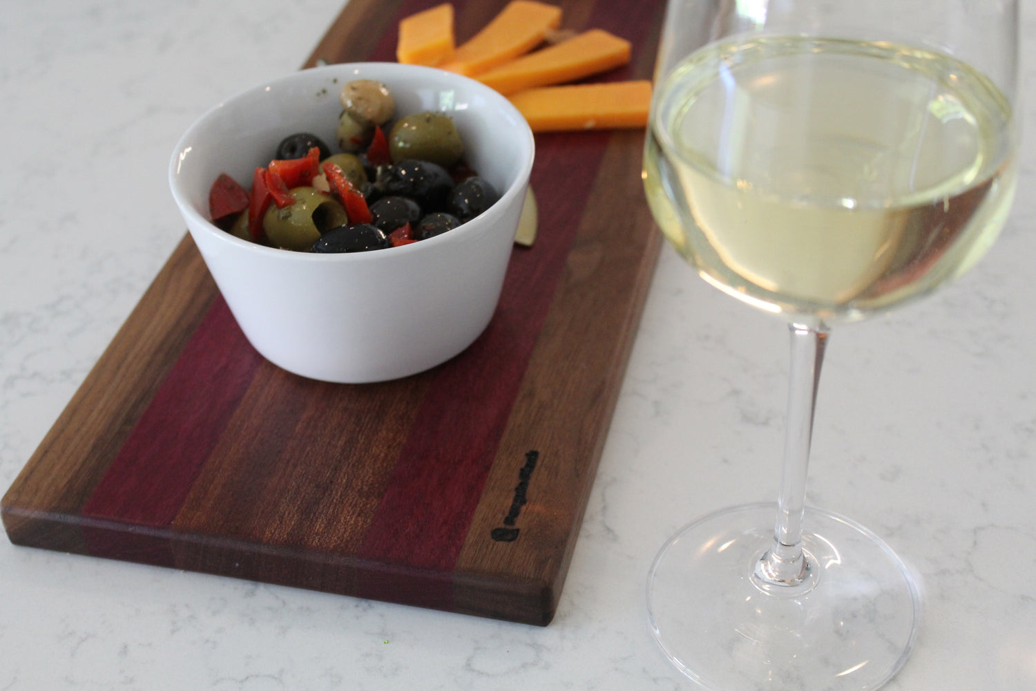 Walnut and purpleheart cutting board with olives, wine and cheese.