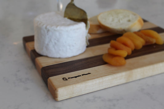 Maple and walnut picnic cutting board with cheese and apricots.