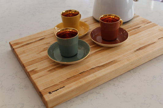 Brown maple cutting board with espresso cups.